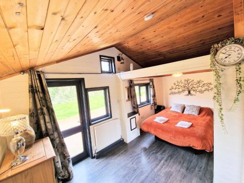 ein Schlafzimmer mit einem Bett und einer Uhr an der Wand in der Unterkunft Otter 2 HuntersMoon- Warminster-Wiltshire-Bristol in Warminster