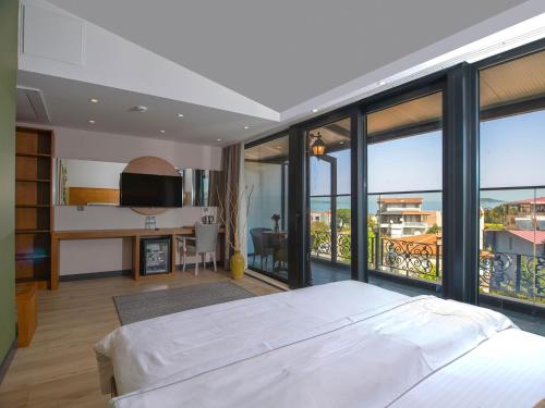 a bedroom with a large white bed and large windows at Maison Vourla Hotel in Urla