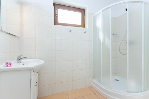 a white bathroom with a shower and a sink at Domki Nautilus-Rowy in Rowy