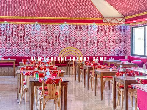 uma sala de jantar com mesas e cadeiras e paredes cor-de-rosa em Rum Laverne Luxury Camp em Wadi Rum