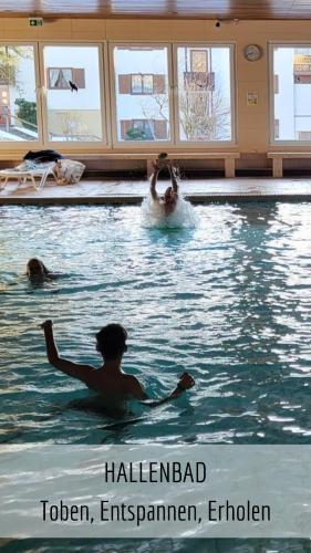 a group of people swimming in a swimming pool at Almchalet mit Pool und Sauna in Missen-Wilhams