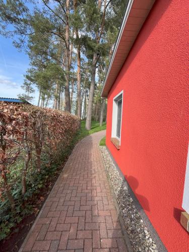 a red building with a brick sidewalk next to a road at Küstenferienhaus Nr. 91/92 in Stahlbrode