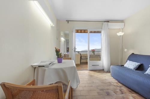 un salon avec une table et un canapé bleu dans l'établissement Le Mas Berliat N°9, à Bormes-les-Mimosas