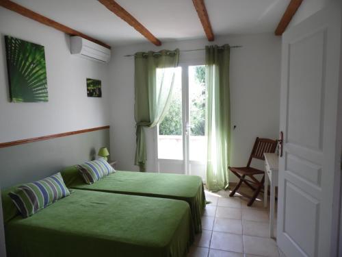 ポルト・ヴェッキオにあるLocations Résidence Rocca Rossa Palombaggiaのベッドルーム(緑のベッド1台、窓付)