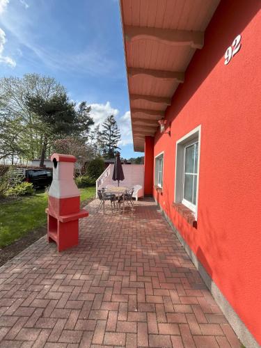 a red building with a patio with a table and an umbrella at Küstenferienhaus Nr. 91/92 in Stahlbrode