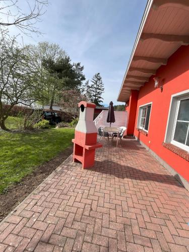 a red house with a brick patio with a fireplace at Küstenferienhaus Nr. 91/92 in Stahlbrode