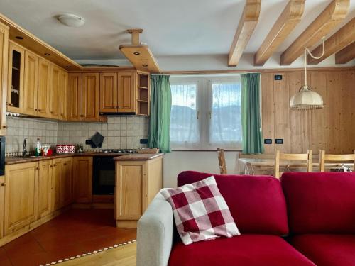 Villa Iris Asiago - giardino e parcheggio في أسياجو: غرفة معيشة مع أريكة حمراء في مطبخ