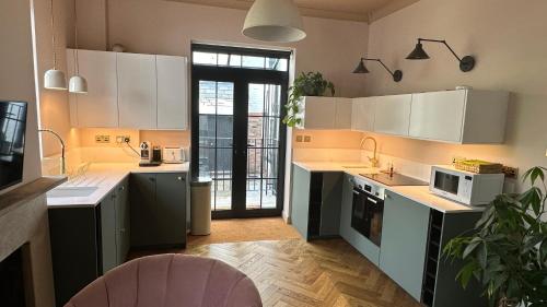uma cozinha com armários brancos e electrodomésticos com uma janela em The Annexe em Stockport