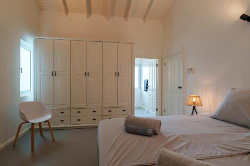 a bedroom with a bed with a chair and a cabinet at Villa Seru JanThiel in Jan Thiel