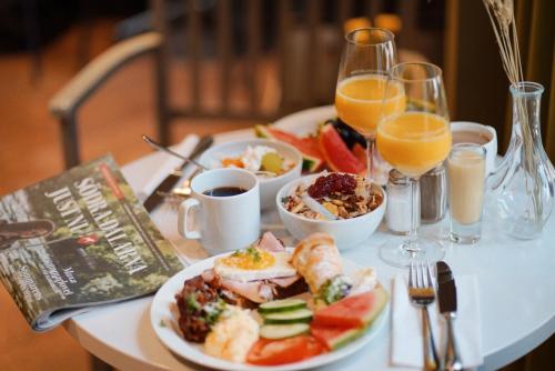 a table with a plate of food and glasses of orange juice at Home Hotel Bergmästaren in Falun