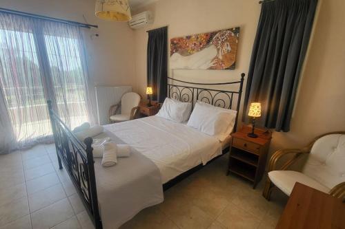 a bedroom with a bed and a chair and window at Βίλα Χαρά in Eretria