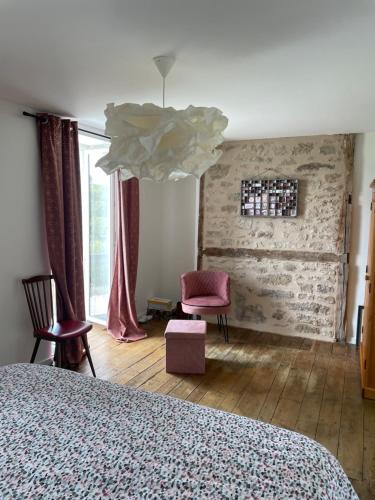 a bedroom with a bed and a pink chair at Gîte de charme avec spa sous les étoiles Corrèze in La Roche-Canillac