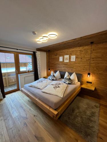 a bedroom with a large bed with a wooden wall at Alpentime Apartments in Neustift im Stubaital