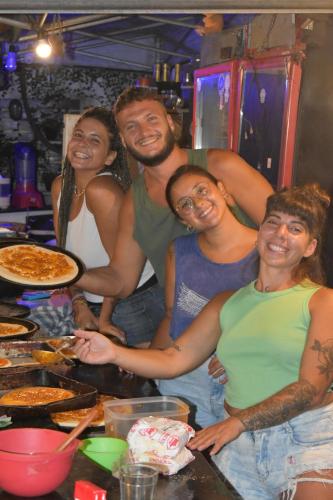 a group of people standing in a kitchen preparing food at Solar Hostel Búzios in Búzios