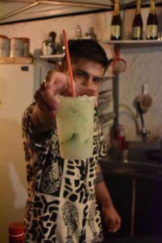 a man is holding up a drink with a straw at Solar Hostel Búzios in Búzios