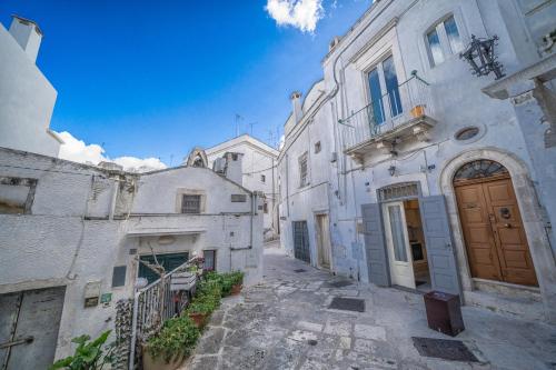 an alley with white buildings and a brown door at Casa Coppaiaia - Spaziosa e luminosa nel centro storico in Martina Franca