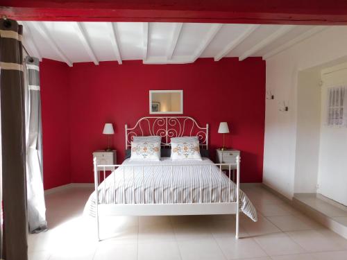 Dormitorio rojo con cama blanca y pared roja en Maison Jules Goux, en Mirmande