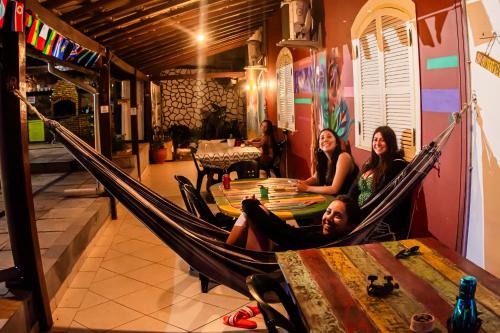 a group of people sitting in a hammock in a room at Solar Hostel Búzios in Búzios