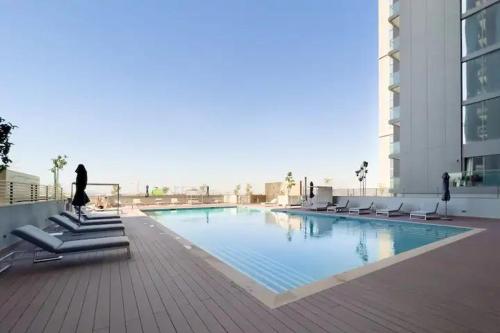 une grande piscine avec des chaises et un bâtiment dans l'établissement Luxury One Bedroom Apartment In The Centre Of Dubai, à Dubaï