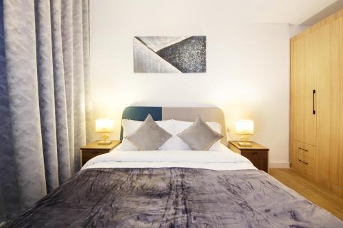ein Schlafzimmer mit einem großen Bett mit zwei Lampen in der Unterkunft Silk Valley - Cozy 1bhk With Pool And Gym in Abu Dhabi