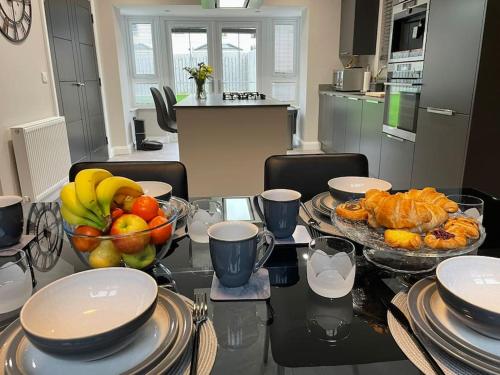 einen Tisch mit einer Schale Obst und einem Teller Essen in der Unterkunft Belfast Luxury: Spacious 2BR Home Near Stormont in Belfast