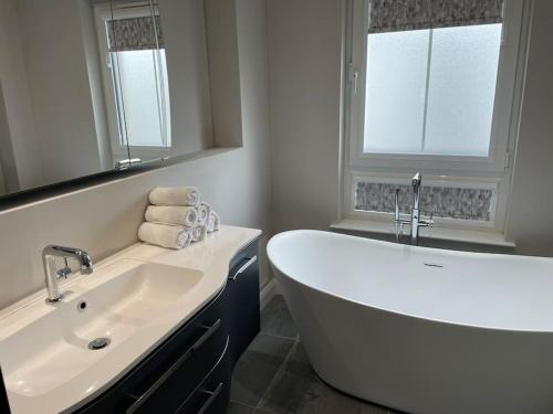 ein Badezimmer mit einer großen weißen Badewanne und einem Waschbecken in der Unterkunft Belfast Luxury: Spacious 2BR Home Near Stormont in Belfast