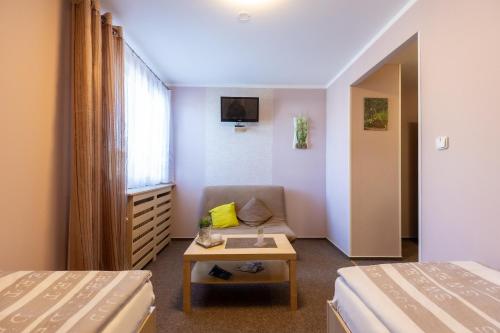 een hotelkamer met 2 bedden en een bank bij Penzion JAAL in Příbor