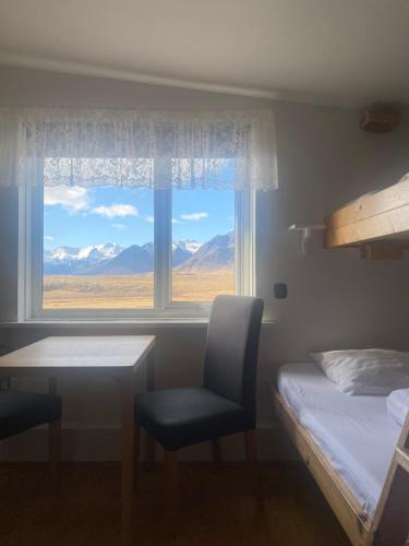 a bedroom with a bed and a desk and a window at Vagnsstadir in Borgarhöfn