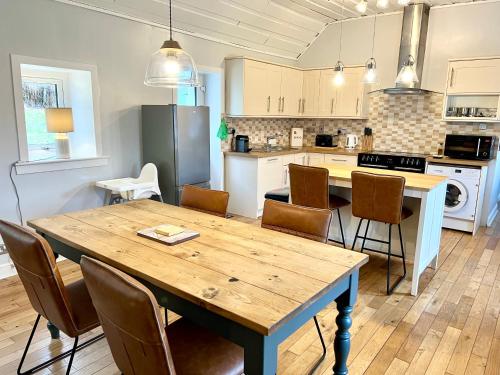 een open keuken met een houten tafel en stoelen bij Owl Cottage - Dog Friendly in Invergarry
