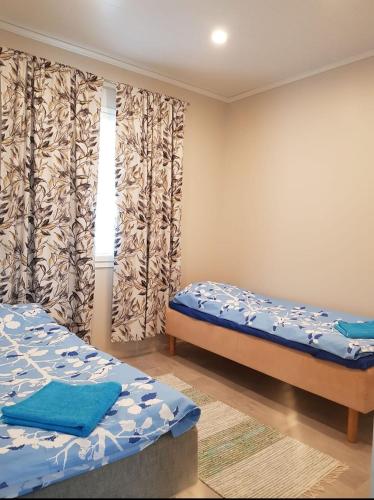 een slaapkamer met 2 bedden en een raam met gordijnen bij Cozy 2-bedroom house close to centre in Haapajärvi
