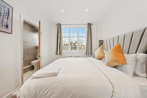 a bedroom with a large white bed with orange pillows at The Grosvenor Residences in London