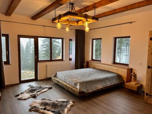 ein Schlafzimmer mit einem Bett in einem Zimmer mit Fenstern in der Unterkunft Tiarra Mountain Lodge in Beliş