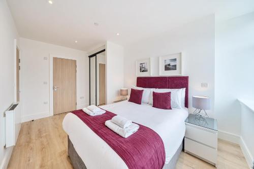 a white bedroom with a large bed with two towels at Roomspace Serviced Apartments- Syward Place in Chertsey