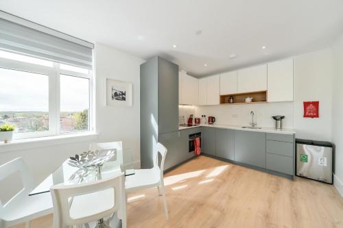 a kitchen with white cabinets and a table and chairs at Roomspace Serviced Apartments- Syward Place in Chertsey