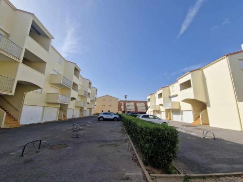 une voiture garée sur un parking à côté de bâtiments dans l'établissement Studio RDC 4 couchages avec terrasse à Marseillan, proche plage, parking privé - FR-1-326-614, à Le Castellas