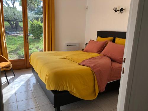 - une chambre dotée d'un grand lit avec des oreillers jaunes et rouges dans l'établissement Villa du Lagon, à Vidauban