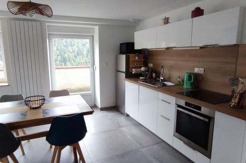 eine Küche mit weißen Schränken, einem Tisch, einem Tisch und Stühlen in der Unterkunft Chez mémé in Engenthal