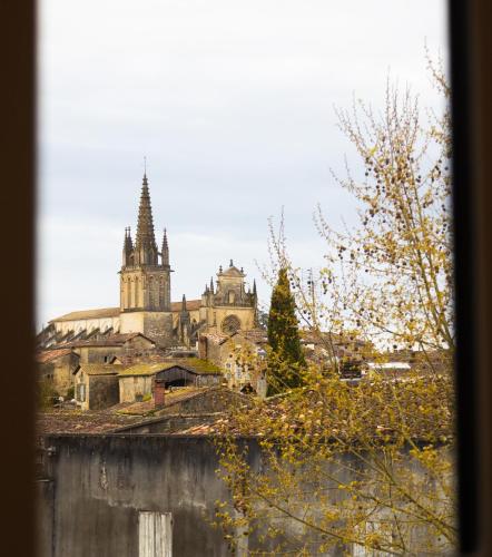 un vieux bâtiment avec une église en arrière-plan dans l'établissement Grande chambre avec SDB privée, à Bazas