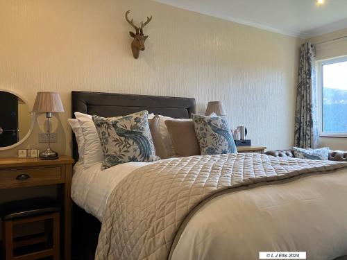 Dormitorio con cama con cabeza de ciervo en la pared en Foyers House, en Foyers