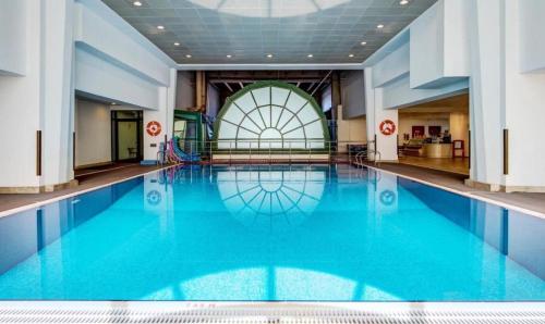 a large swimming pool with blue water in a building at Luxury Awaits: Master Bedroom for Rent! Indulge in comfort and style. in Sharjah