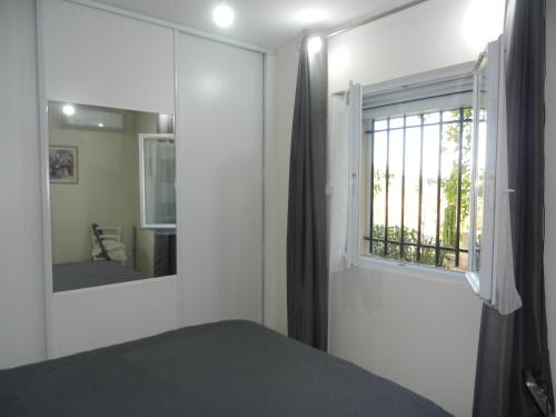1 dormitorio con ventana, cama y espejo en L'Oliveraie, en Draguignan