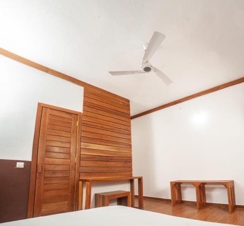 HOROKO HOTEL في نوسي بي: غرفة نوم مع مروحة سقف وجدار خشبي