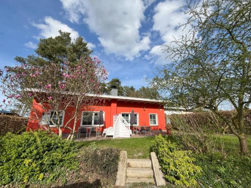 a red house with trees and bushes in front of it at Küstenferienhaus Nr. 91/92 in Stahlbrode