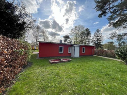a small red house in a grassy yard at Küstenferienhaus Nr. 91/92 in Stahlbrode