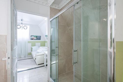 a glass shower in a bathroom with a couch at Appartement Emeraude - Paris à 13 minutes in Deuil-la-Barre