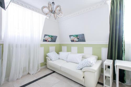 a living room with a white couch and a chandelier at Appartement Emeraude - Paris à 13 minutes in Deuil-la-Barre