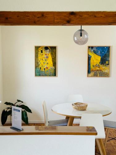 a table and chairs in a room with paintings on the wall at A14 Three Bed Apartment City Center in Heidenheim an der Brenz