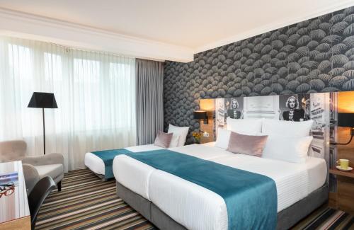 a hotel room with two beds and a chair at Leonardo Boutique Hotel Berlin City South in Berlin
