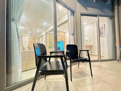 two chairs and a table in a room with windows at The Sóng Hotel & Apartment Vũng Tàu in Vung Tau