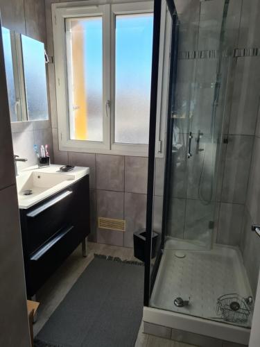 ein Bad mit einer Dusche und einem Waschbecken in der Unterkunft Résidence de la plage in Ouistreham